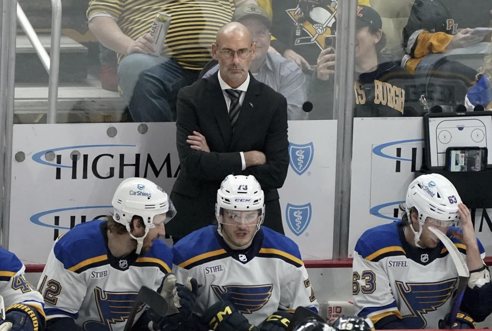 FILE - St. Louis Blues interim head coach Drew Bannister stands behind the bench during the first period of an NHL hockey game against the Pittsburgh Penguins, Saturday, Dec. 30, 2023, in Pittsburgh. The St. Louis Blues have removed the interim tag from Drew Bannister’s title and named him their full-time coach. President of hockey operations and general manager Doug Armstrong announced the move Tuesday, May 7, 2024.
